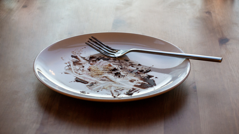 A plate with the remains of a chocolate fudge cake and a fork