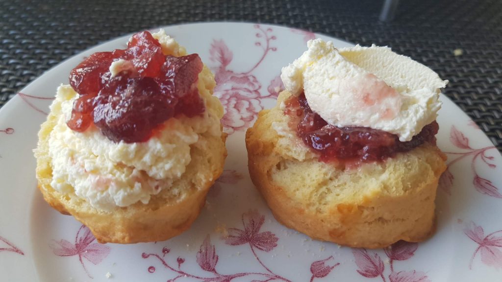 Two scone halves, one with jam then cream, the other with cream then jam.