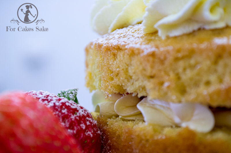 A slice of a victoria sandwich cake with fresh cream and a strawberry garnish